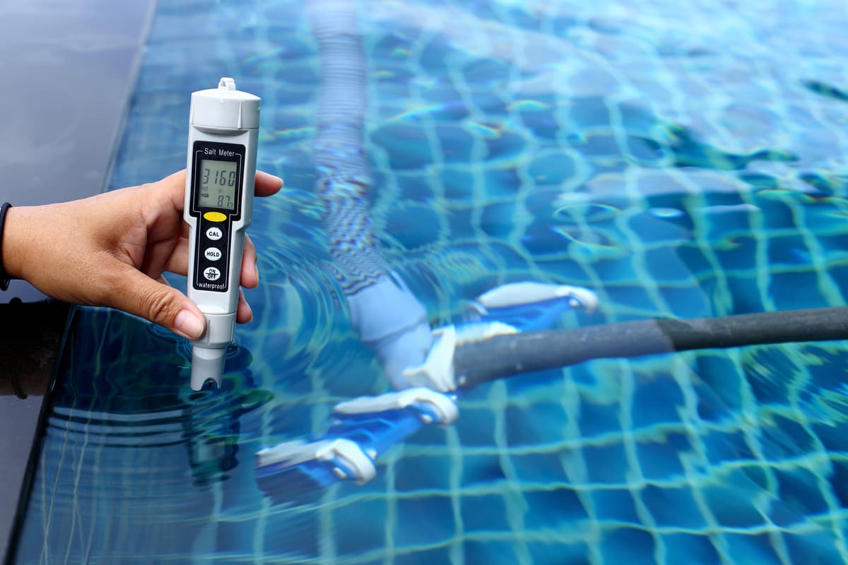Digital water testing meter held in a swimming pool during chemical analysis